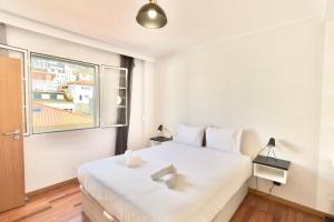 a bedroom with a white bed and a window at Serena Bay in Câmara de Lobos