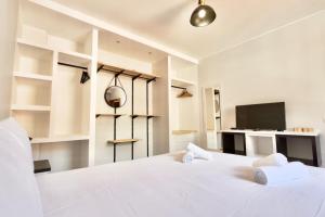 a white bedroom with a large bed and a tv at Serena Bay in Câmara de Lobos