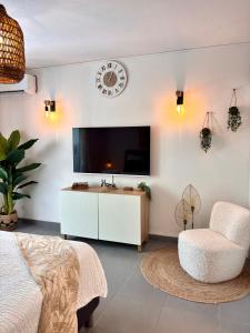 una camera da letto con una tv, una sedia e un orologio di Cottage de Pinel Terrasse & Piscine tropicale a Cul de Sac Altre 21 foto