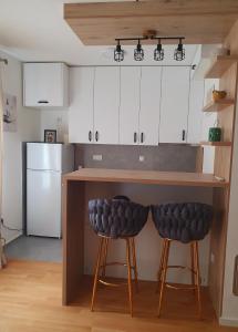 a kitchen with a counter with two stools under it at Apartman v&n in Vranješ