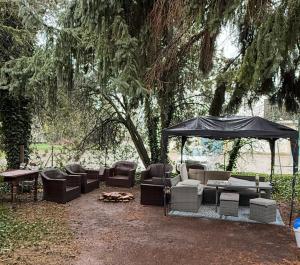 a gazebo with couches and chairs under a tree at Apartmány Karlov Dvor in Trnava