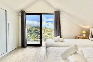 a bedroom with two beds and a large window at Anna-Marie House in Ponta do Sol