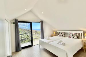 a bedroom with a white bed and a large window at Anna-Marie House in Ponta do Sol +15 photos
