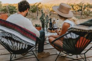 a man and woman sitting at a table with bottles of wine at Campera Valle de Guadalupe in Ensenada