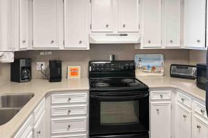 a kitchen with white cabinets and a black stove at Dunescape Villas 252 in Atlantic Beach