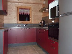 Una cocina con gabinetes rojos y un microondas. en Les Noisettes, en La Bresse