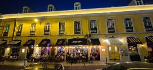 a group of people sitting outside of a yellow building at Studios with Mezzanine Rua da Moeda in Lisbon