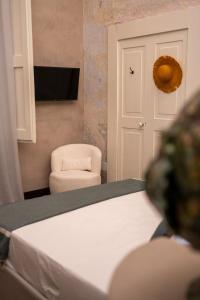 a bedroom with a bed and a chair and a television at Fundacari B&b in Gallipoli