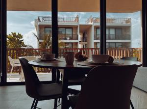 a table with chairs and coffee cups on a balcony at Golden Hour 2BR Ocean View Apt in Holbox Island