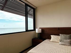 a bedroom with a bed and a large window with the ocean at Golden Hour 2BR Ocean View Apt in Holbox Island +12 photos