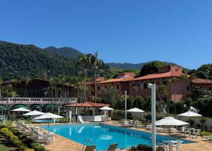 a resort with a swimming pool with chairs and umbrellas at Hotel Recanto dos Pássaros in São Sebastião