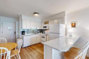 a kitchen with a white refrigerator and a table and chairs at Seaspray 242 in Atlantic Beach