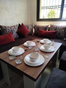 a wooden table with plates and wine glasses on it at Le Refuge de Vittel 2 in Ifrane +12 photos