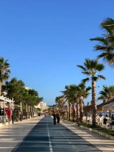 a boardwalk with palm trees and people walking down it at DURRES SEA SIDE Big Family Apartament in Durrës