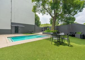 un patio trasero con mesa, sillas y piscina en Charming Studio & Backup Power, en Johannesburgo