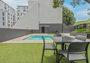 Un patio con sillas y una mesa y una piscina. en Charming Studio & Backup Power, en Johannesburgo