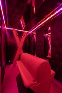 Un sofá rojo en una habitación con luces rosas. en Espace évasions Loft love LOVE ROOM, en Toulouse