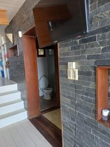 a bathroom with a toilet and a tv on a brick wall at La mejor vista del Rivero - Entre Dos Mares - Punat del Diablo in Punta Del Diablo