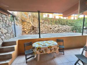 a patio with a table and chairs and a stone wall at Appartamento Rosè in San Teodoro
