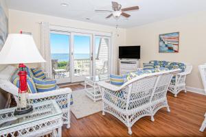 a living room with white wicker chairs and a television at PKOG09 Ocean Grove G4 in Pine Knoll Shores