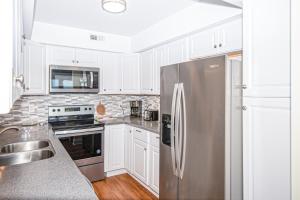 a kitchen with white cabinets and a stainless steel refrigerator at PKOG09 Ocean Grove G4 in Pine Knoll Shores