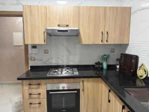 a kitchen with a stove and wooden cabinets at trqnche 5 imm k rsd no 189 riad essalam in Tangier
