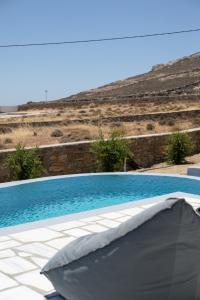 a swimming pool in front of a hill with a hillside at Ventus Studios in Ano Mera