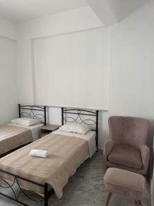 a bedroom with two beds and a chair at Nitsa Rooms in Kos Town