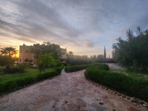 a path in a park with a building and trees at La dolce villa in Aït Bou Zguia