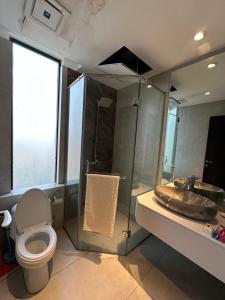 a bathroom with a toilet and a shower and a sink at The Gulberg Apartments in Lahore +3 photos