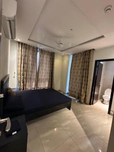 a room with a bed and a toilet and curtains at The Gulberg Apartments in Lahore