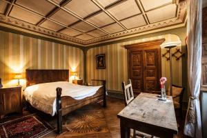 Un dormitorio con una cama y una mesa. en Palazzo Gamboni Swiss Historic Hotel, en Comologno