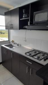 a kitchen with a stove and a microwave at Vacaciones muy cerca al Parque del Cafe in Montenegro