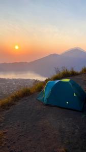 クブペンロカンにあるMount Batur Camping on Summitの夕暮れの丘の上に立つ青いテント
