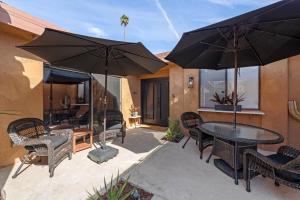 a patio with a table and chairs and umbrellas at Designer Seville Condo w Golf Mountain Views in Rancho Mirage