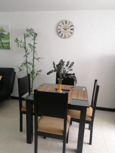 a dining room table and chairs with a clock on the wall at Alojate a 3 minutos del Parque del Cafe in Montenegro