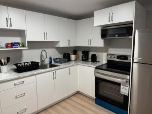 a kitchen with white cabinets and black appliances at Tommy Place in Moncton