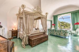 a bedroom with a canopy bed and a couch at Villa Calypso in Capri