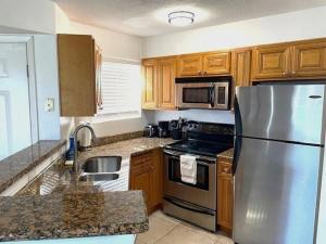 a kitchen with a stainless steel refrigerator and wooden cabinets at Relaxing Condo with Heated Pool in Indialantic +14 photos