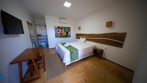 a bedroom with a bed and a desk and a television at Bosque Cumbuco Pousada in Cumbuco