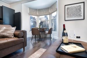 a living room with a couch and a table with a bottle of wine at Lake Road Apartments in Bowness-on-Windermere
