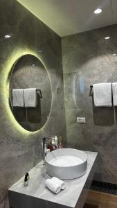 a bathroom with a large round mirror and a tub at The Grand in Nardaran