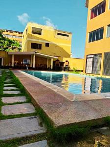 a building with a swimming pool in front of a building at Arena, Mar y Amaneceres para Siete frente a Farmatodo tucacas in Tucacas