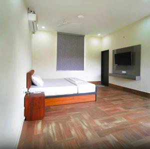 a bedroom with a bed and a flat screen tv at Rocopie Farm in Rohtak