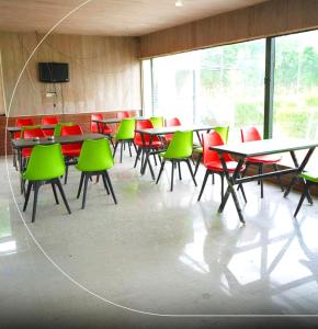 a room with tables and green chairs in a classroom at Rocopie Farm in Rohtak