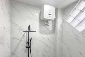 a white bathroom with a soap dispenser on a wall at Urbanview Olive Near Graha Saba Buana Surakarta in Bonorejo
