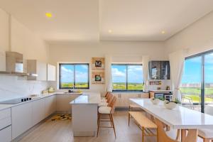 Una cocina con gabinetes blancos y una mesa y sillas. en New! Luxury PH with Pool Golf & Ocean Views, en Punta Cana