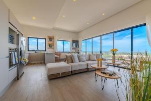 Una sala de estar con un sofá, mesas y ventanas. en New! Luxury PH with Pool Golf & Ocean Views, en Punta Cana