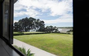 a window view of a field of grass and a road at Bay View Terrace Studio 3 in Tataraimaka