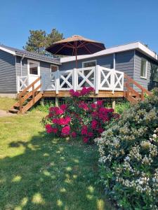 a house with a porch with an umbrella and flowers at Well-Located Holiday Home In Ristinge, Langeland in Humble